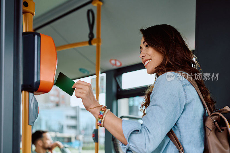 在乘坐公共交通工具时使用电子卡的快乐女子。