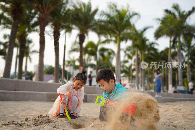 两个可爱的亚洲孩子在沙滩上堆沙堡