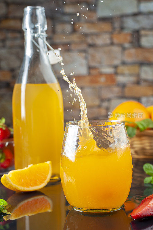 溅起的橙汁饮料与水果和果汁瓶在背景