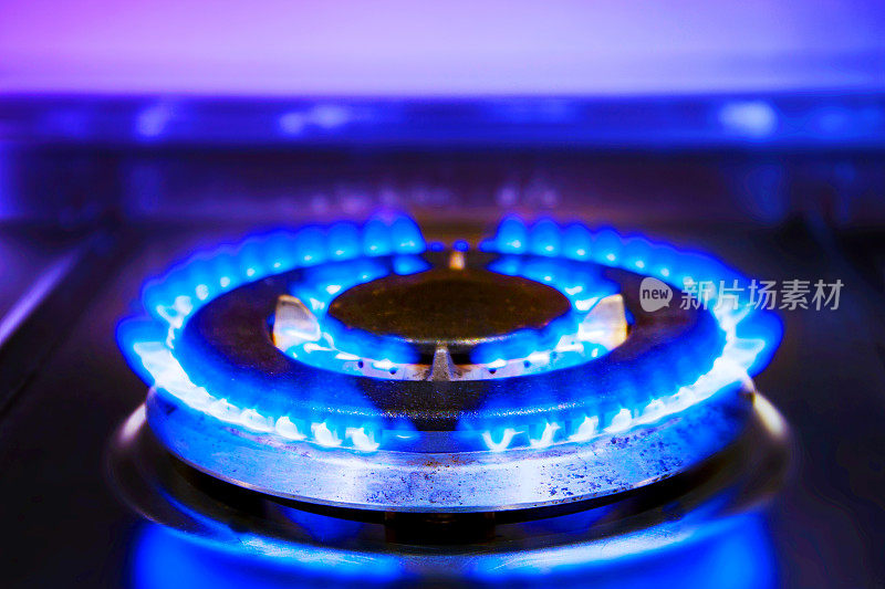 燃烧着蓝色气体火焰。燃烧着的厨房煤气炉。煤气炉已经点燃，厨房里有两个灶具。大型煤气灶燃烧器。