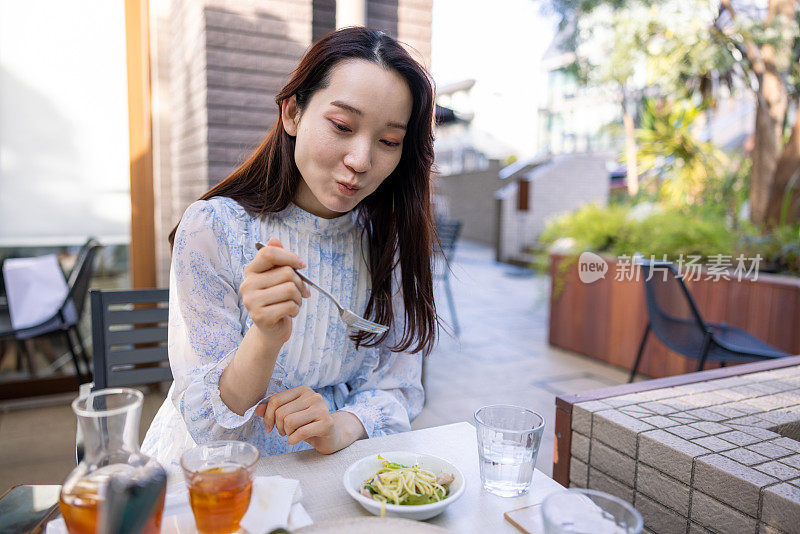 年轻女子在户外咖啡馆吃意大利面