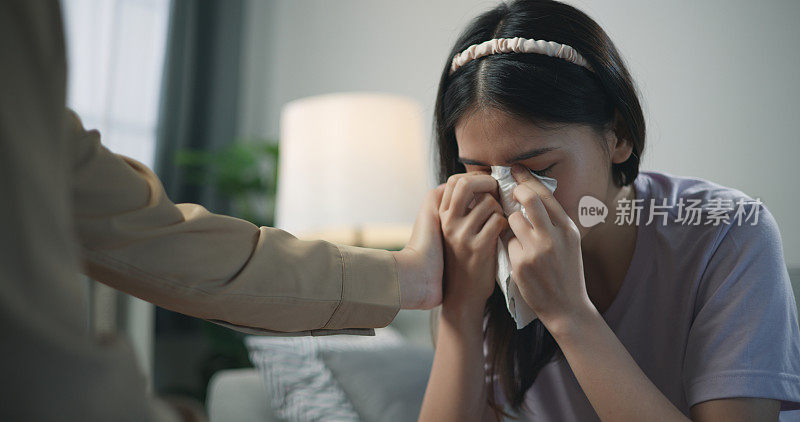 年轻的专业治疗师一边哭泣一边抚摸女病人的肩膀