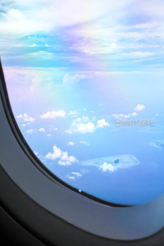 透过窗户看飞机在机翼飞行，有一个美丽的蓝天和岛屿。飞机窗外的景色。白天阳光灿烂的白天。