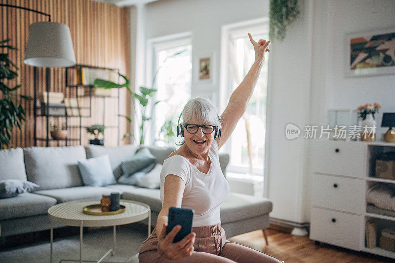 一位老年妇女在家里一边听音乐一边锻炼