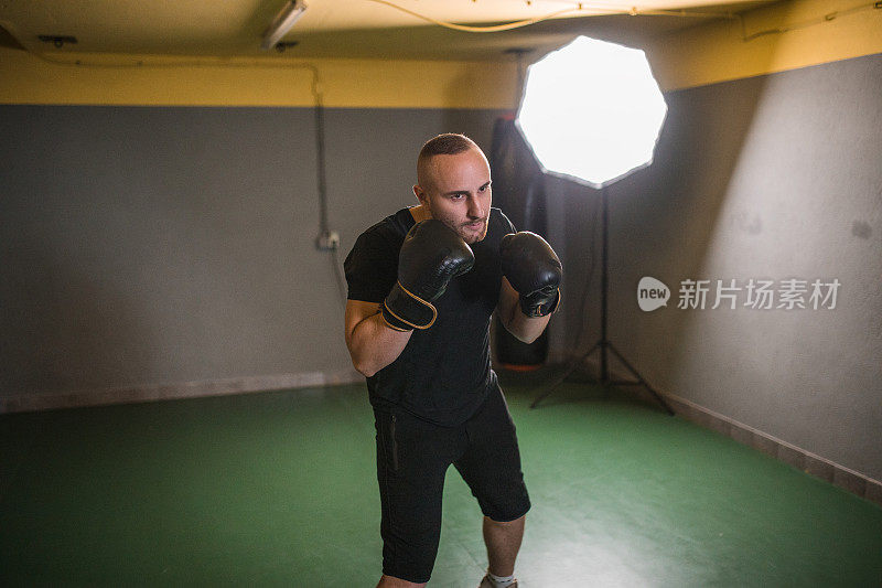一个强壮而上进的男拳击手在健身房训练，为拳击比赛做准备