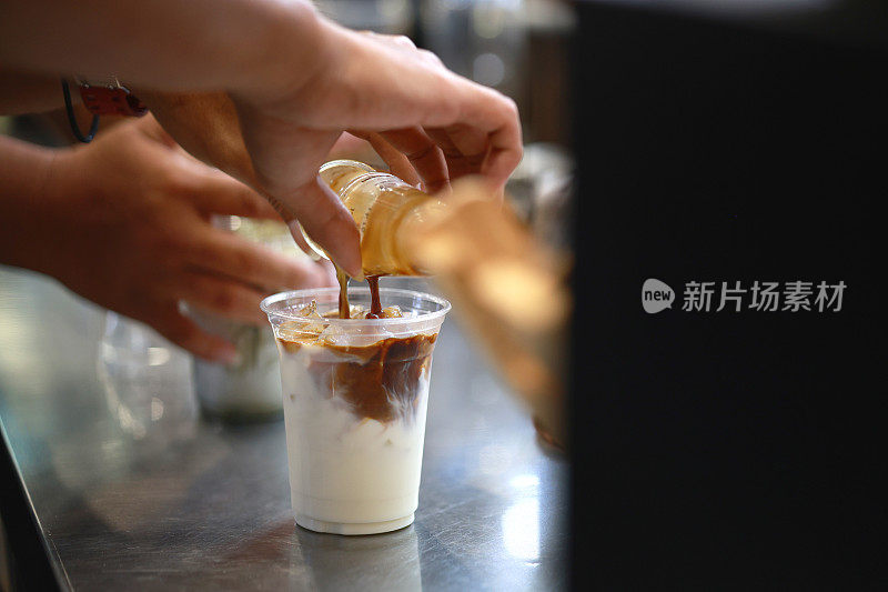用手将浓缩咖啡倒入冷牛奶中，制作冰拿铁。