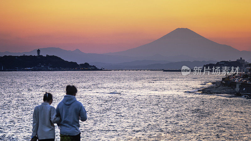 黄昏的宁静:一对夫妇在神奈川海岸欣赏富士山。