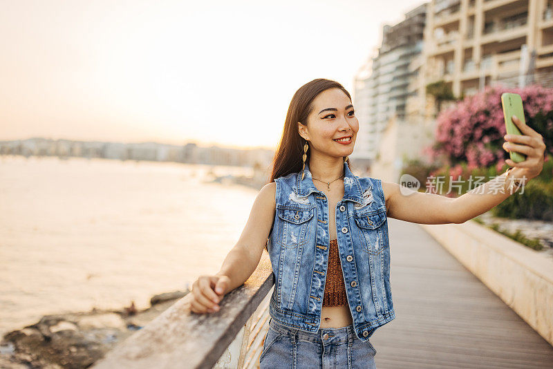 一名亚洲女子用手机自拍，欣赏周围的自然风光