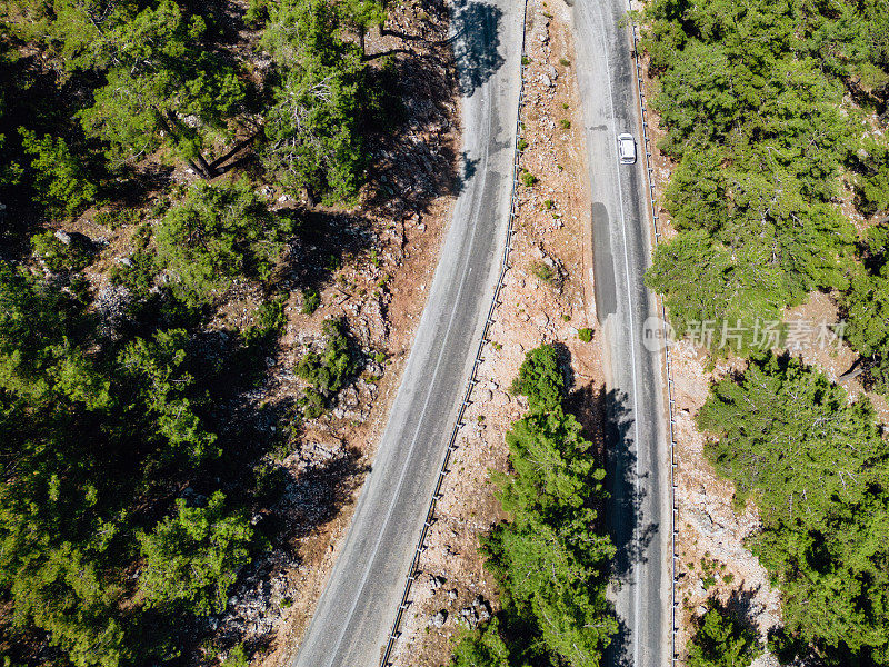 在森林山区的道路上行驶的车辆用无人机拍摄沥青弯道