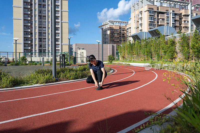 一个女人正在跑道上系鞋带