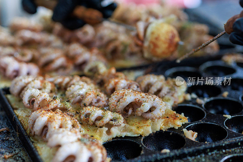 厨师在热锅上烹饪章鱼烧，日本流行的街头小吃。