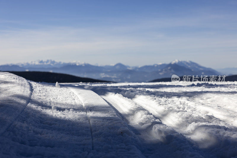 积雪覆盖的越野滑雪道与山在远处