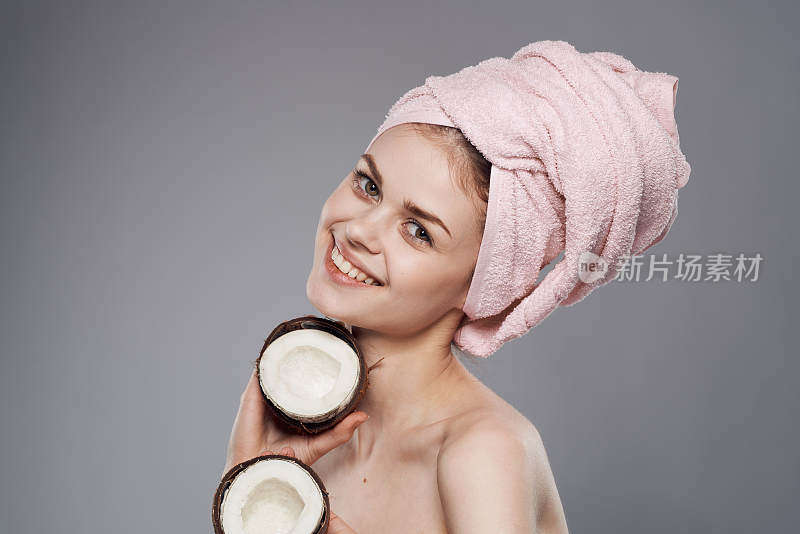 欢快的女人拿着椰子在她的手裸露的肩膀天然化妆品治疗皮肤护理