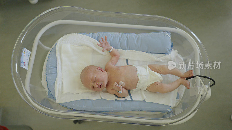正上方的照片是赤裸上身的可爱婴儿躺在医院病房的保温箱里