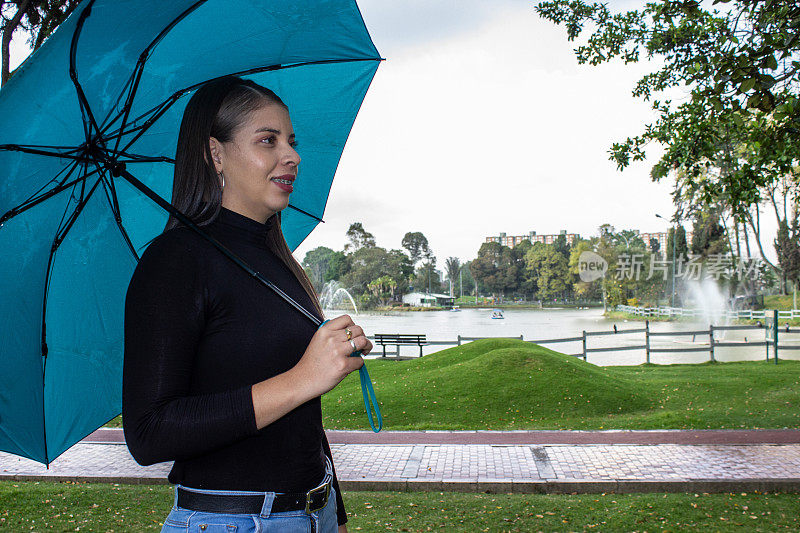 公园里一个漂亮的年轻女子在湖边撑着伞