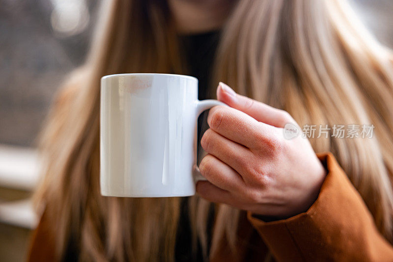 无法辨认的年轻白人女人，手里拿着白色的咖啡杯
