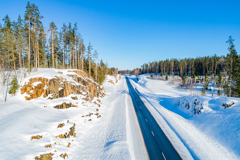 路俄罗斯。高速公路远离城市。大自然在路边。道路铺设在针叶林附近。俄罗斯的高速公路。卡累利阿旅游。车道延伸到远处。冬天的风景。雪