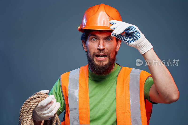 穿着工作服的男子手里拿着橙色的油漆绳，努力工作