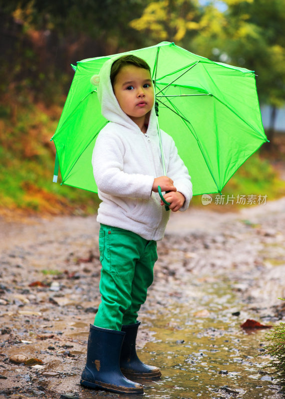 小女孩撑着伞在雨中