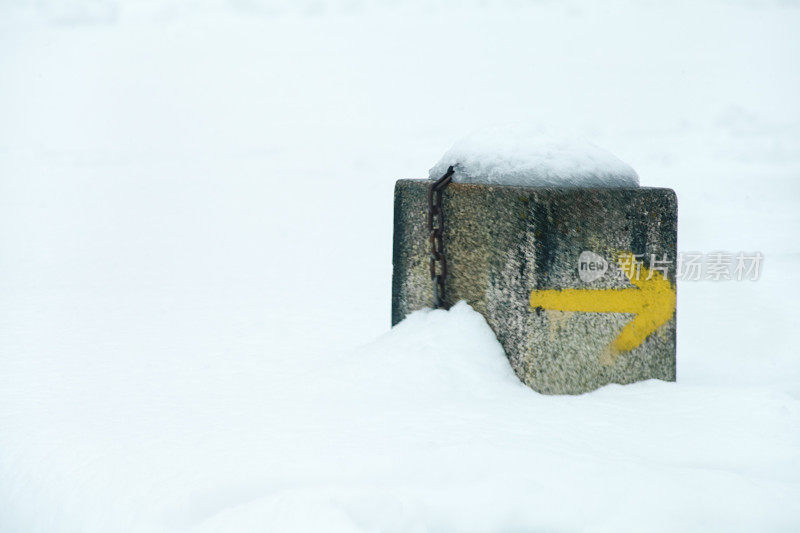 圣地亚哥卡米诺的里程碑被雪覆盖，黄色箭头。