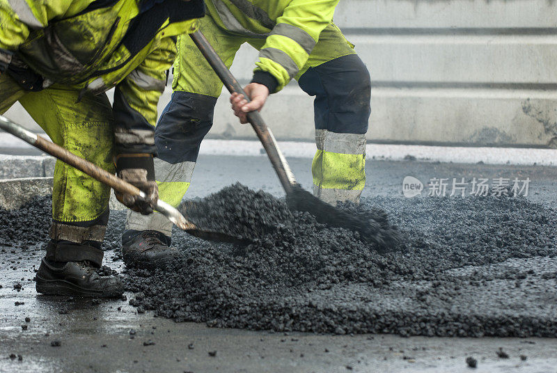 在道路建设中，工人们正在用铁锹制造沥青