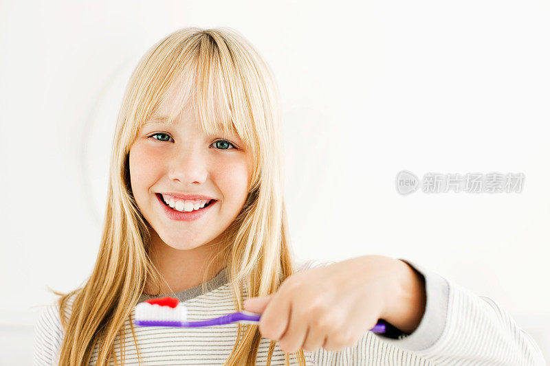 小女孩微笑着，拿着牙刷