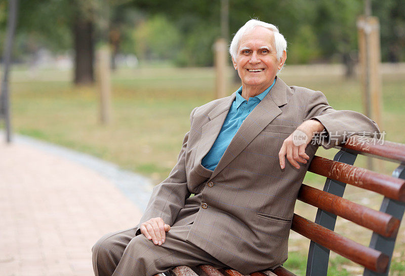 坐在户外长椅上的快乐的老人。