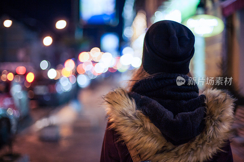 孤独的女孩走在夜晚的城市街道上