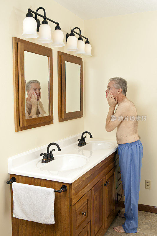 在浴室里洗脸的男人