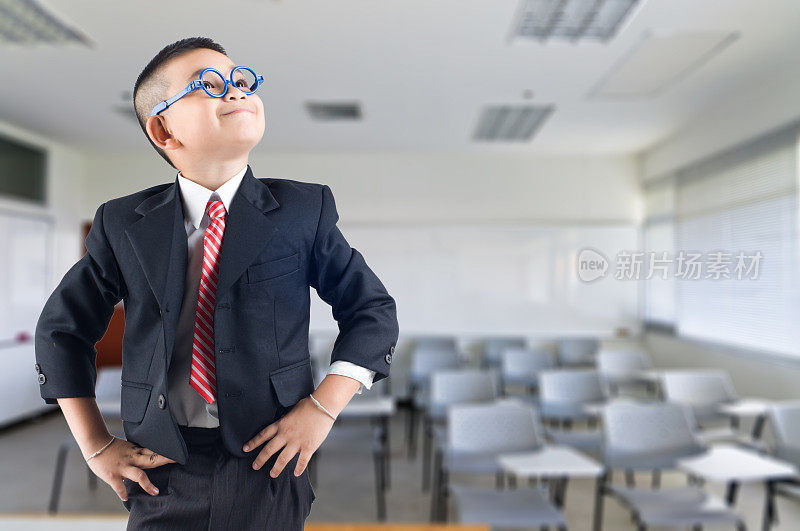 快乐微笑的小商业男孩在教室的背景
