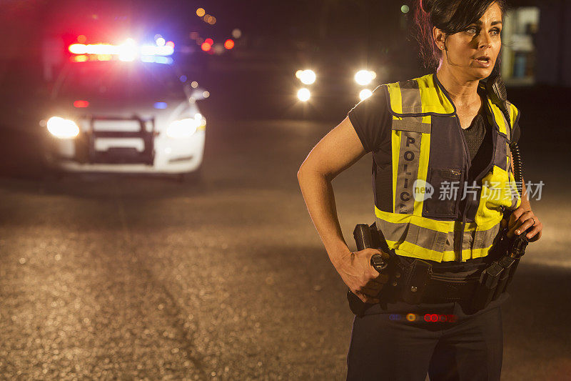 晚上有女警察在街上巡逻，后面是警车