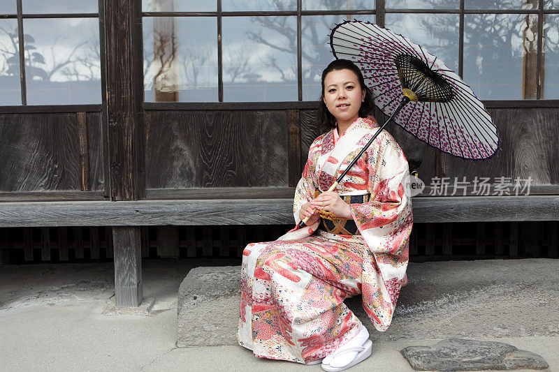 穿着和服的女人拿着伞对抗传统的日本房子