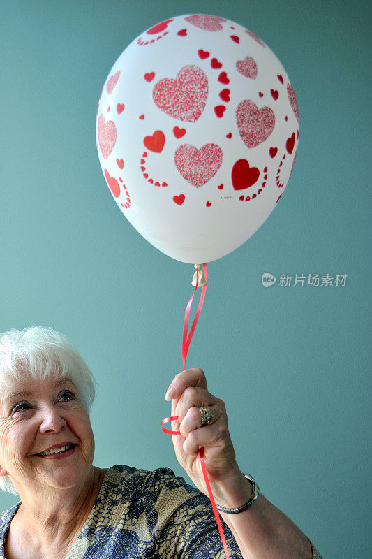 漂亮的老女人拿着红桃气球