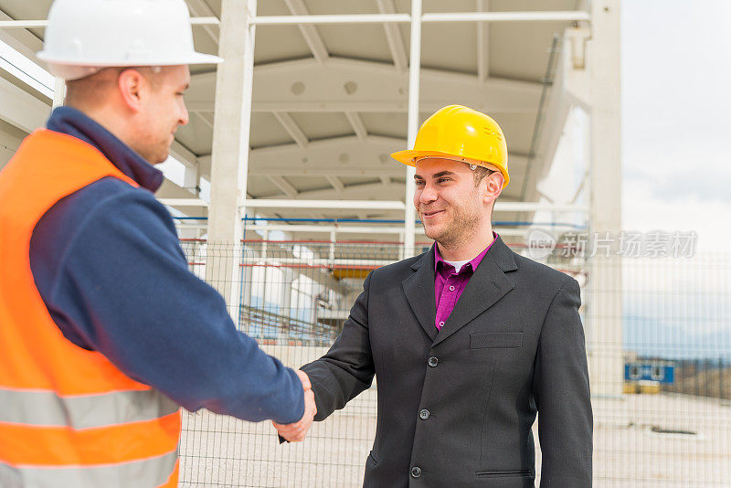 建筑师和建筑工人握手。