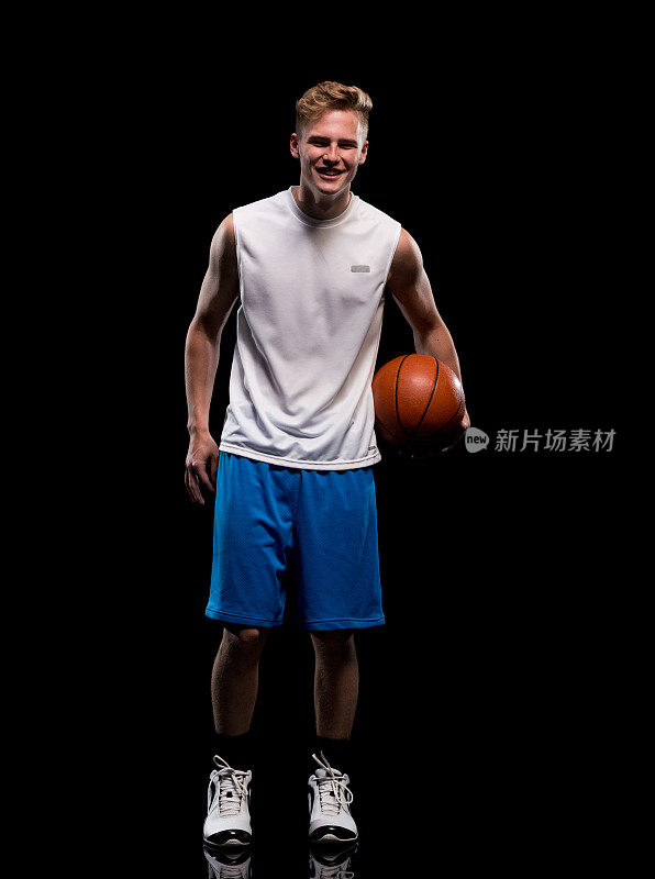 微笑的男运动员拿着篮球