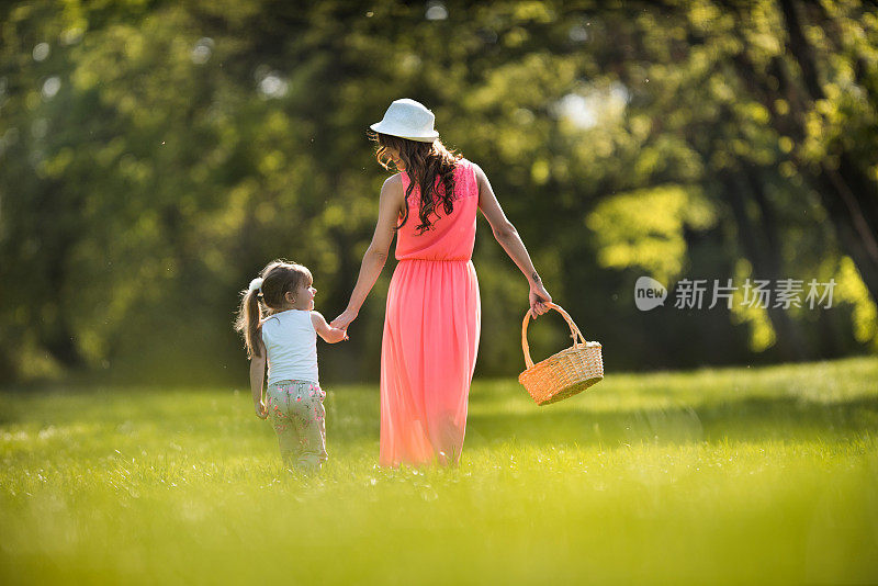 母亲和女儿在大自然中行走的背影。