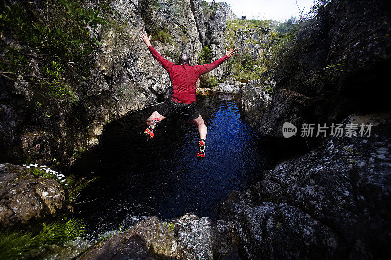 一名男子从岩石上跳入水潭，形成峡谷