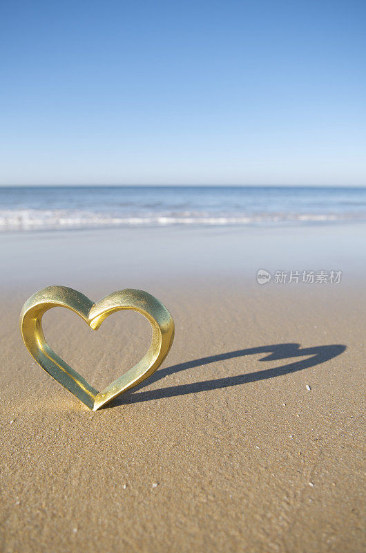 金色的心闪耀在纹理的棕色沙子上