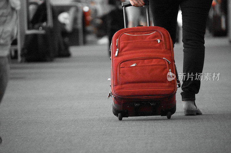 带着一个红色行李箱在机场