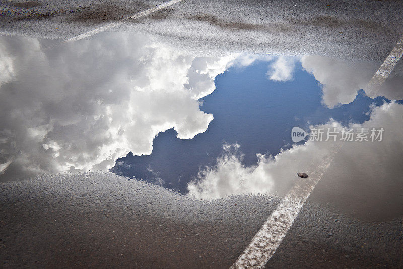 天空和云朵倒映在水坑里