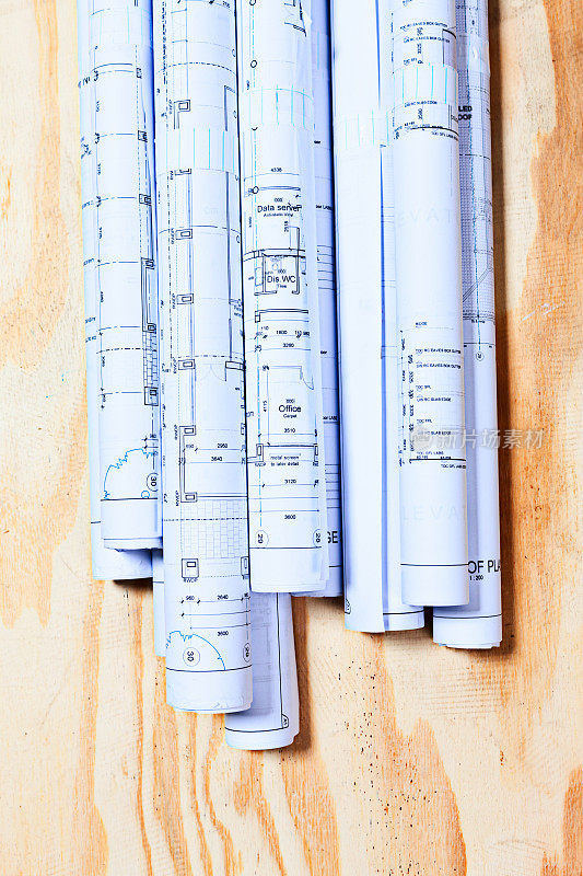 木质背景上整齐地卷起来的建筑平面图