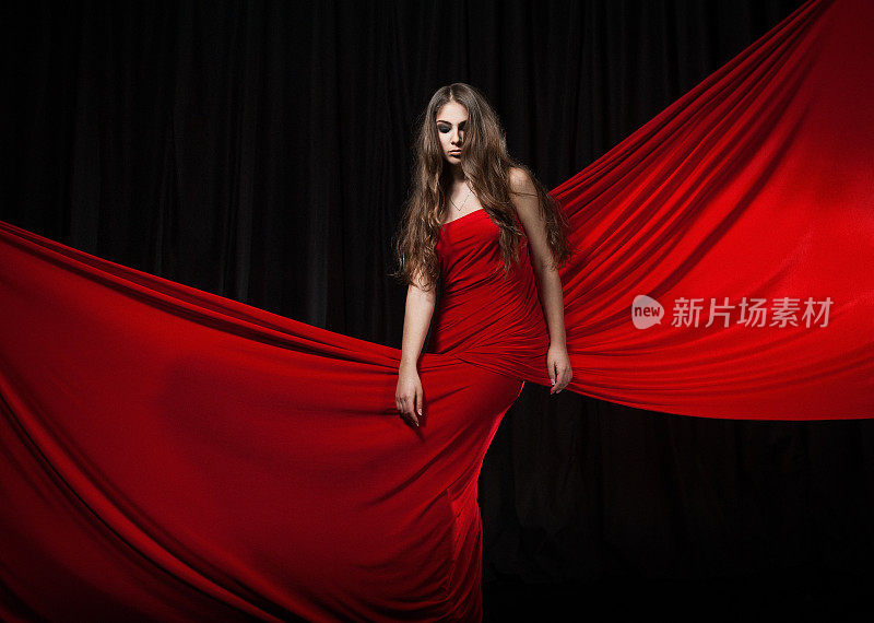 美丽的时装模特跳舞红色连衣裙，红色优雅的丝绸长袍飘扬的面料