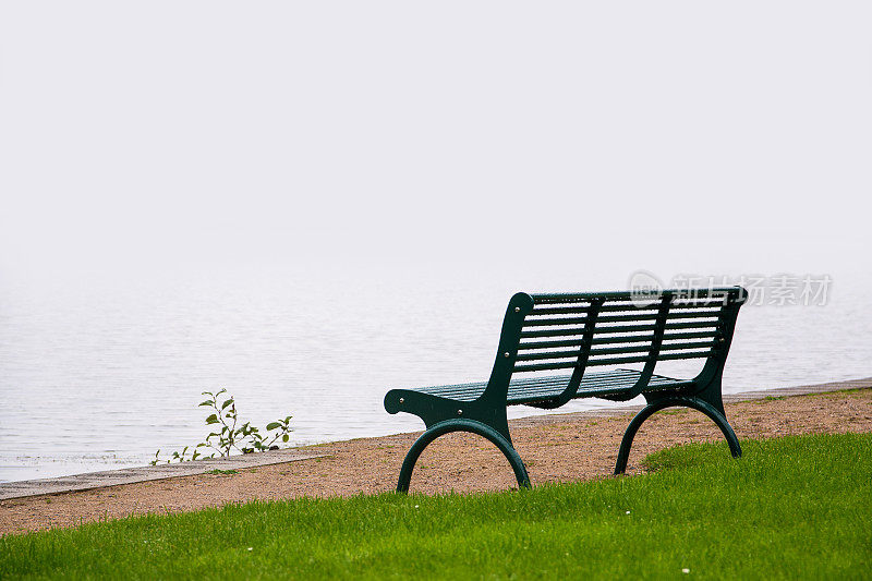 空旷的公园长椅，雾气蒙蒙的湖面上被雨淋得湿漉漉的