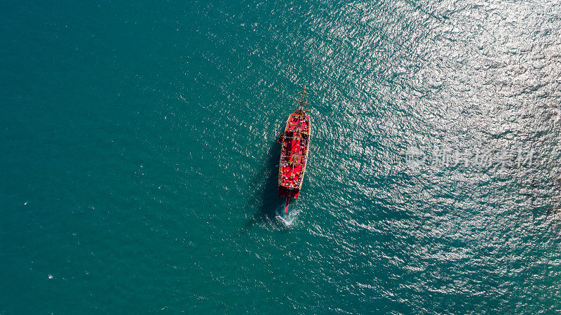 一艘帆船在碧绿清澈的海水中间行驶