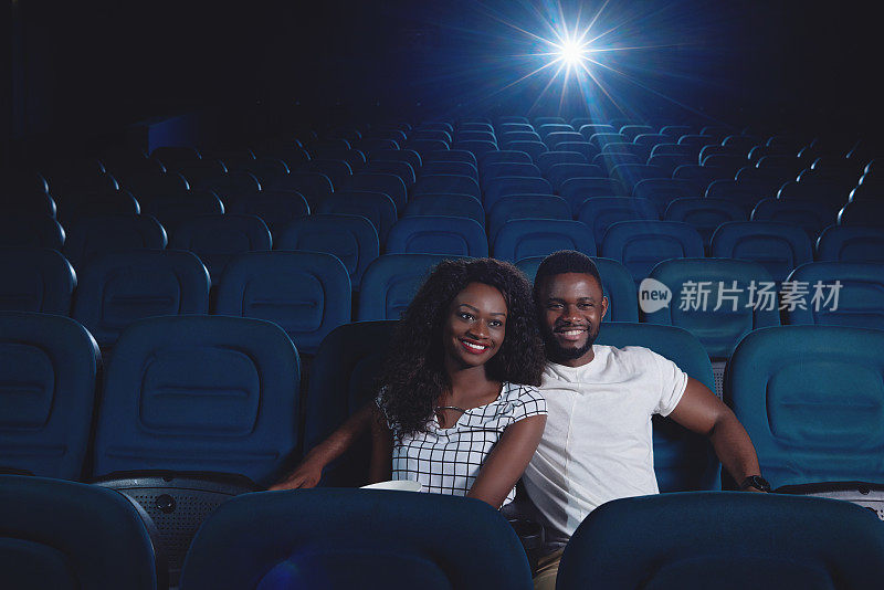 一对在电影院看电影的非洲人。