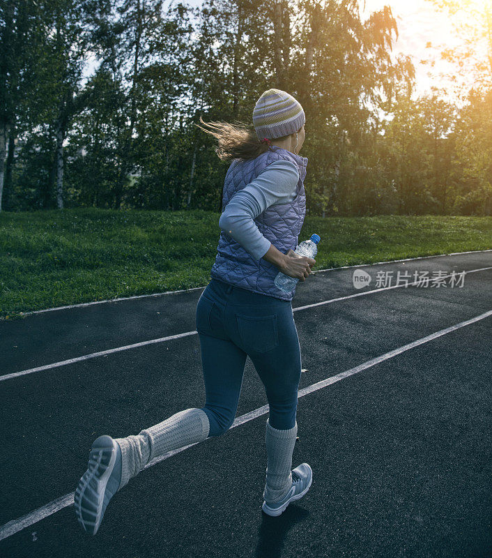 在体育场跑道上跑步的女人