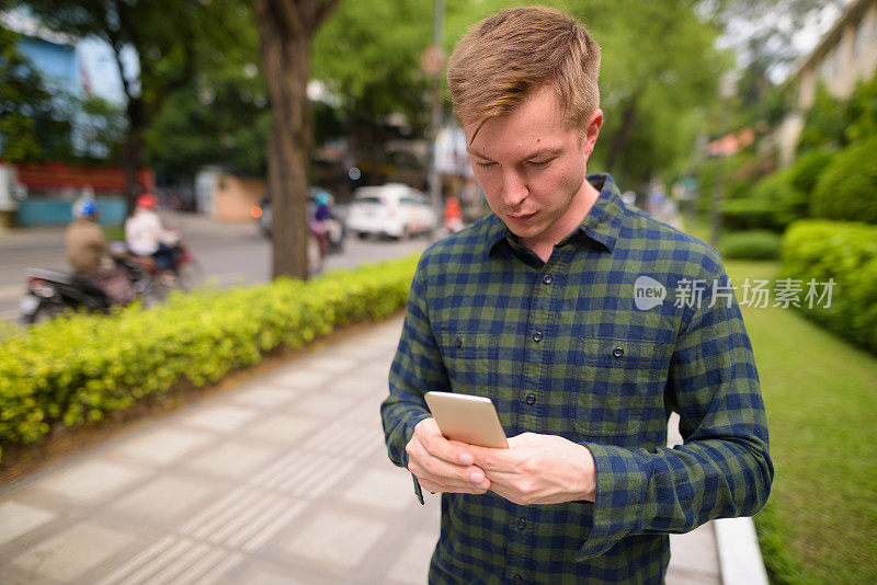 越南胡志明市的街道上，年轻帅气的游客正在使用手机