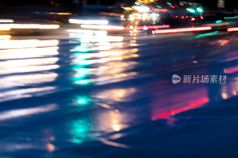 模糊的城市交通前灯反射在潮湿的道路上