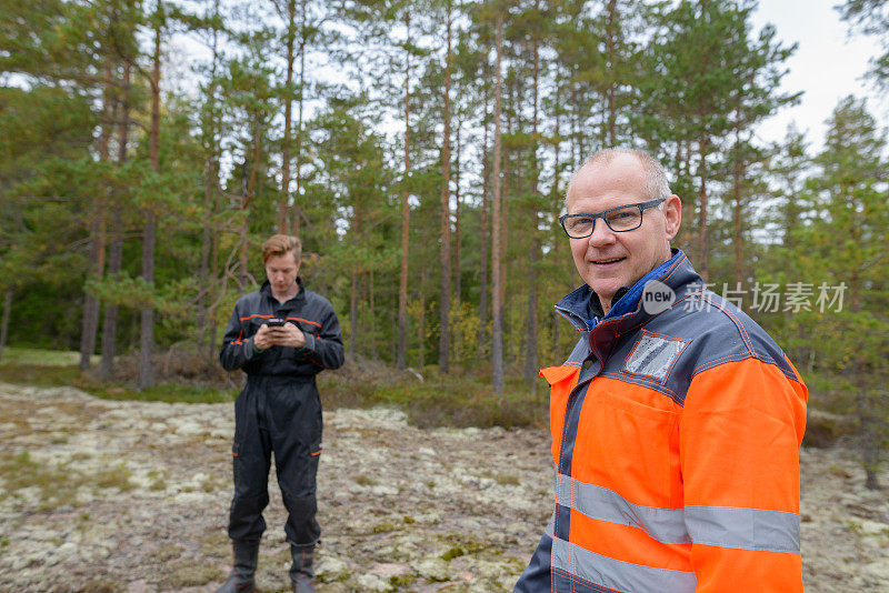 一个成熟的男人和一个年轻的男人一起在森林里工作
