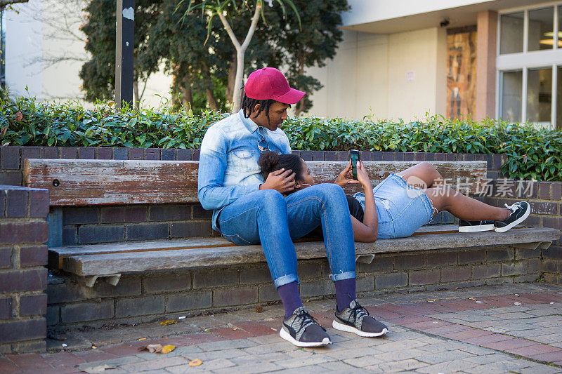 年轻的黑人夫妇放松与他们的手机